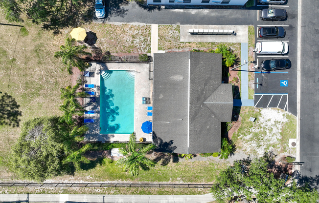 Inviting aerial view of a luxurious apartment complex with a sparkling outdoor pool, surrounded by lush greenery and convenient parking.