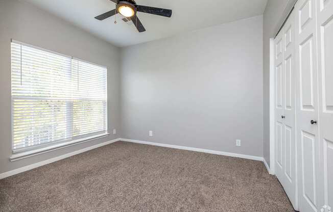 A room with a ceiling fan and carpeted floor.