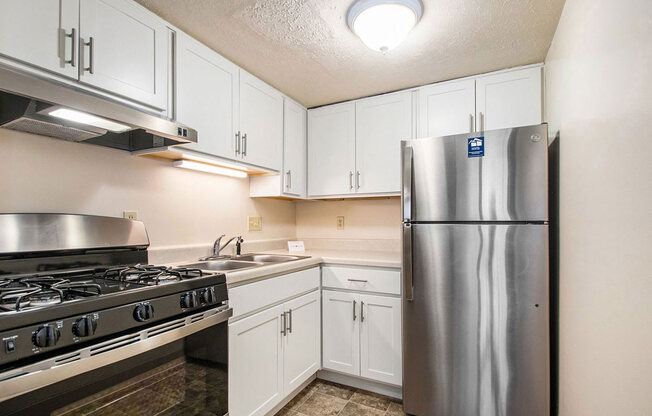studio kitchen with stainless steel appliances and white cabinets