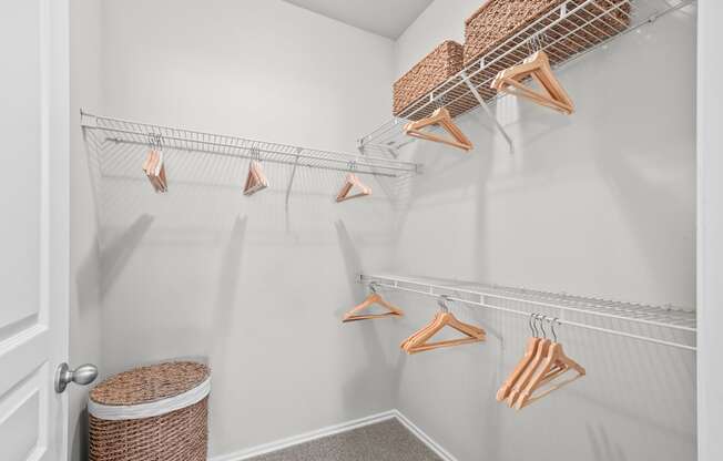 A white closet with clothes hanging on hangers.