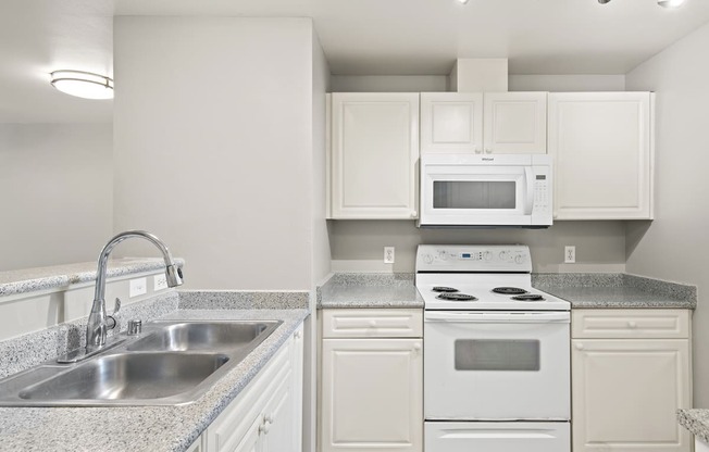 an empty kitchen with white appliances and granite counter tops