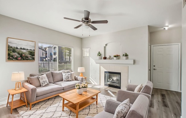 A living room with a grey couch, a coffee table, and a fireplace.