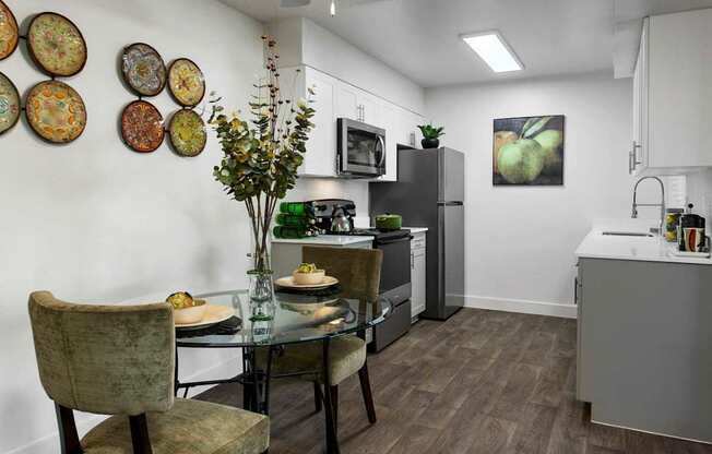 A kitchen with a table set for two and a vase of flowers.
