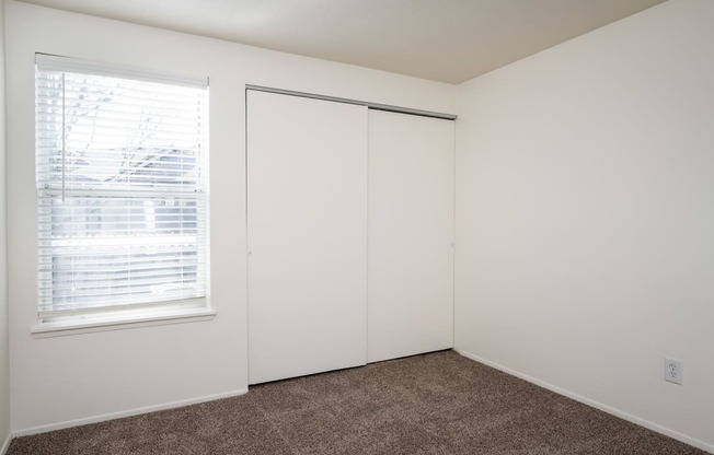 a bedroom with white walls and a window with blinds