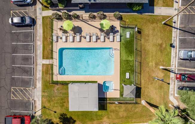 an aerial view of a swimming pool in a park with a fence