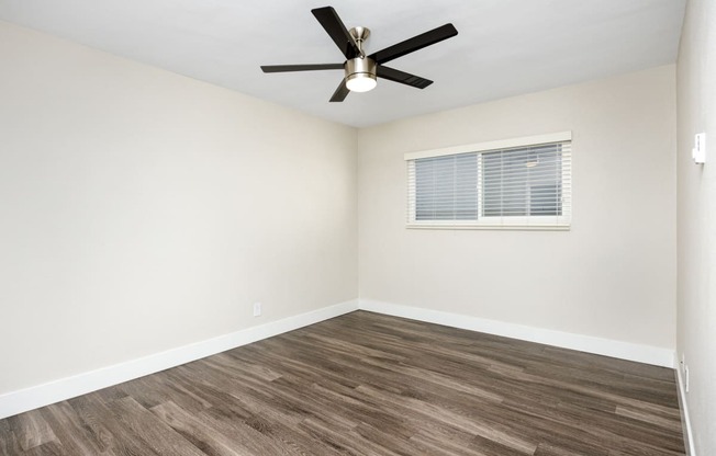 an empty room with a ceiling fan and a window
