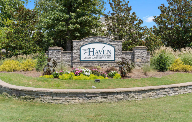 a stone retaining wall with a sign in front of it that says the heaven lawn and garden