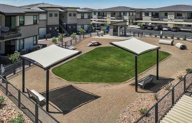 A large grassy area surrounded by buildings and a metal fence.