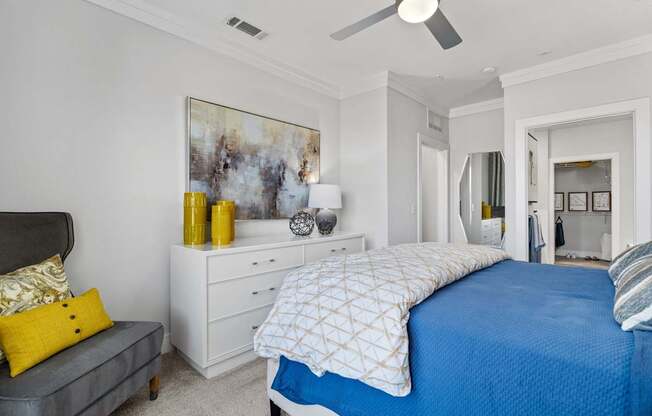 A bedroom with a blue bedspread and a grey headboard.