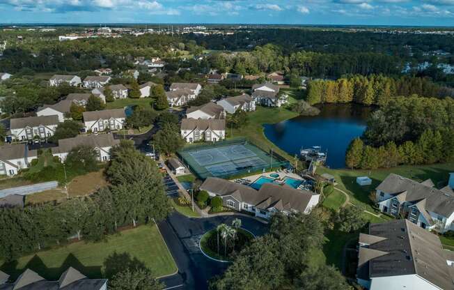 an aerial view of a neighborhood with a tennis court and a lake