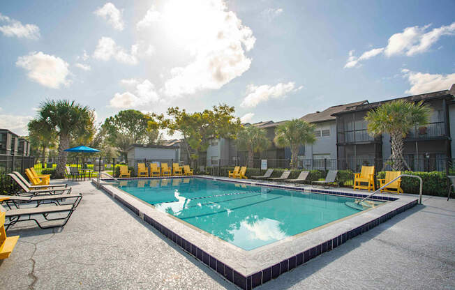 A sunny day at the pool with yellow lounge chairs.