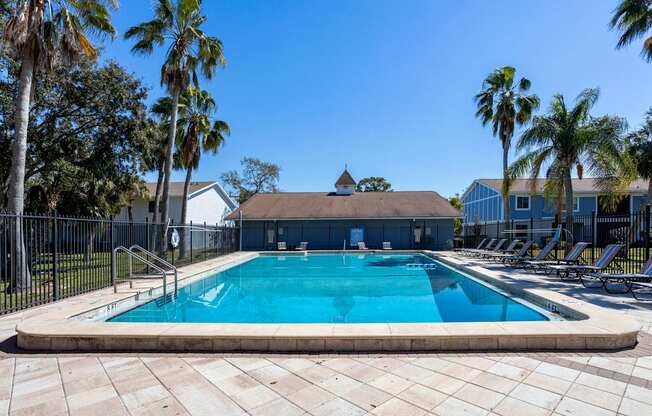 A swimming pool surrounded by palm trees and a fence.