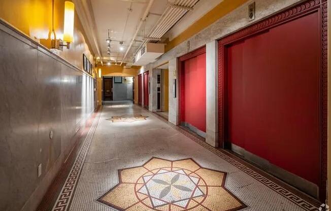 A long hallway with a tiled floor and a rug with a flower design in the middle.