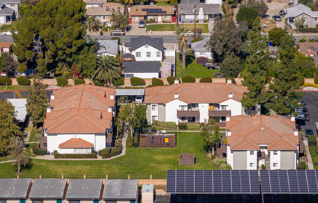 A neighborhood with a large house in the center and solar panels on the roof.