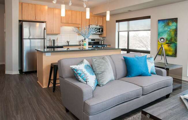 A modern kitchen with a grey couch and a painting on the wall.