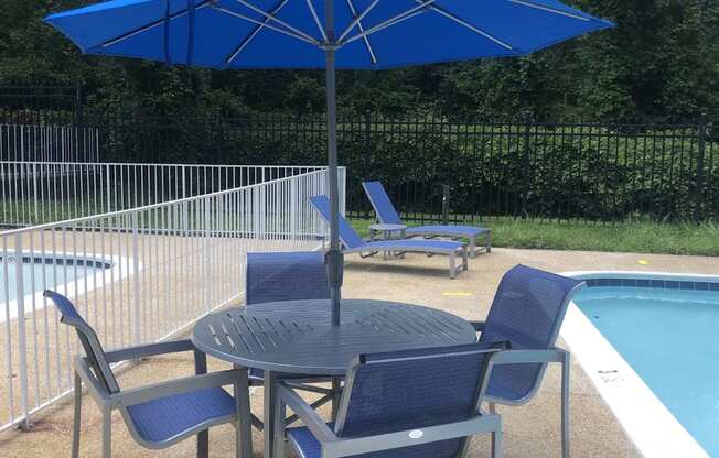 A blue umbrella is above a round table with four chairs.