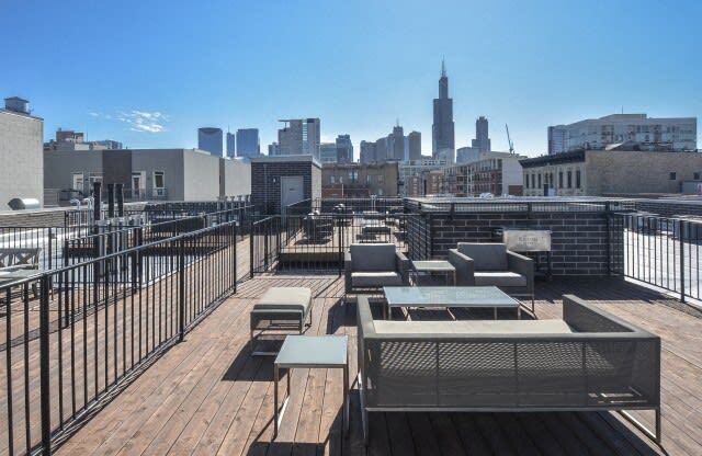 the top of a roof deck with picnic tables and a view of the city
