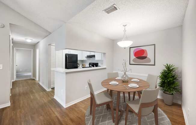 a dining area with a table and chairs and a kitchen in the background