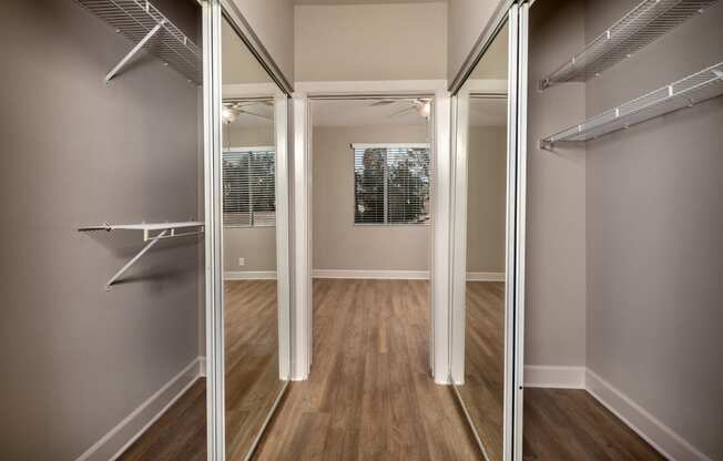 a walk in closet with mirrored mirrored closet doors and a window
