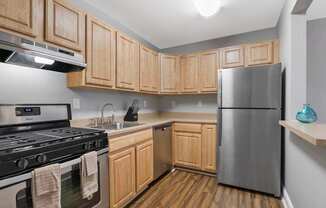 A kitchen with wooden cabinets and a stainless steel refrigerator.