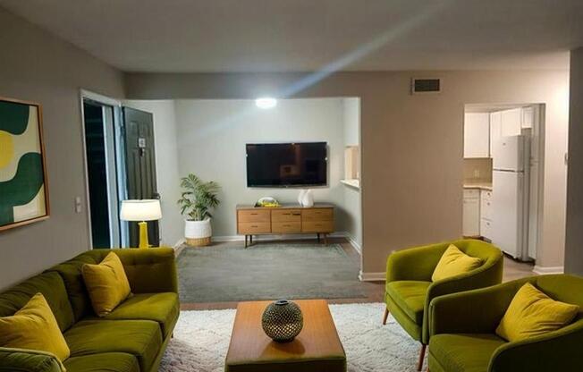 A living room with a green couch, a coffee table, and a television.