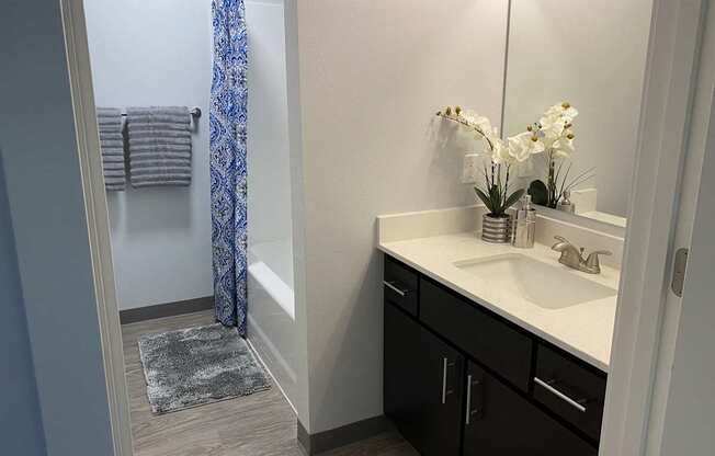 A bathroom with a sink, mirror, and a shower with a blue curtain.