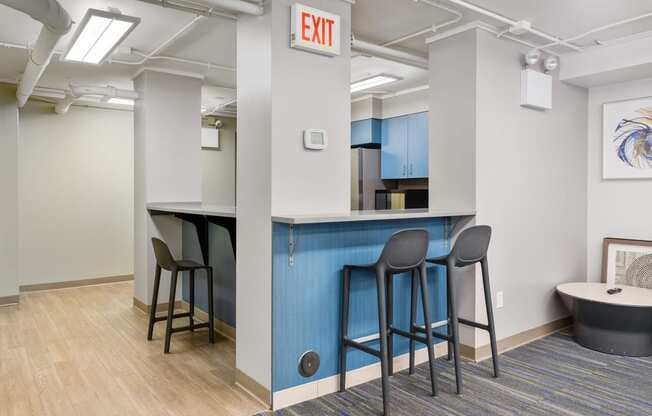 a bar area with stools and a kitchen in the background