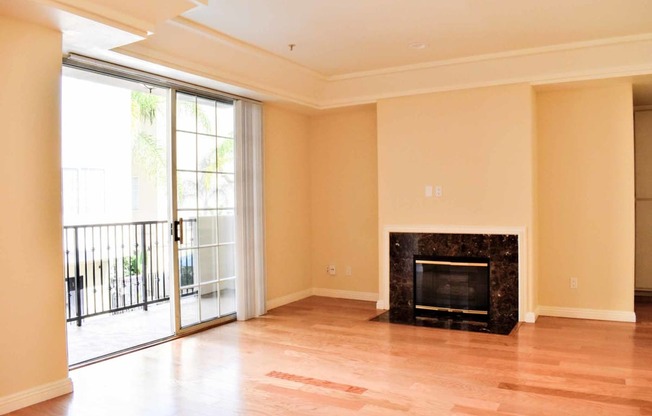 View from dining into living area and private patio/balcony with wood look flooring and fireplace