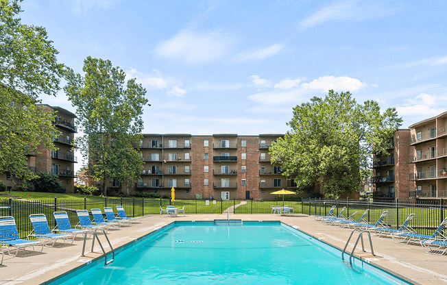 a swimming pool with blue chairs and a building in the background