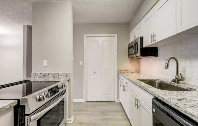 a renovated white kitchen with white cabinets and granite counter tops and a sink at Veridian at Sandy Springs