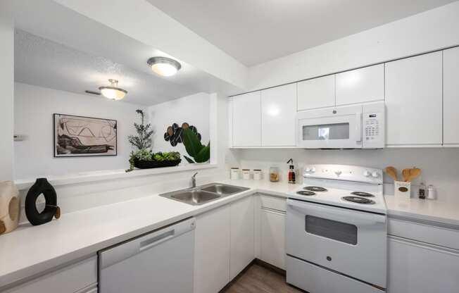 a kitchen with white appliances and white cabinets and a sink