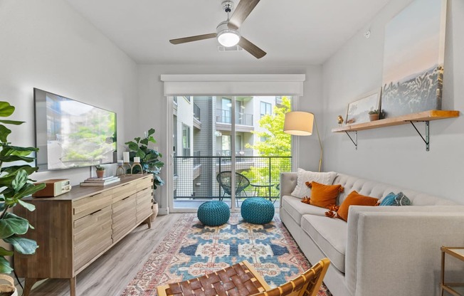 A living room with a white couch, a wooden dresser, a ceiling fan, and a rug.