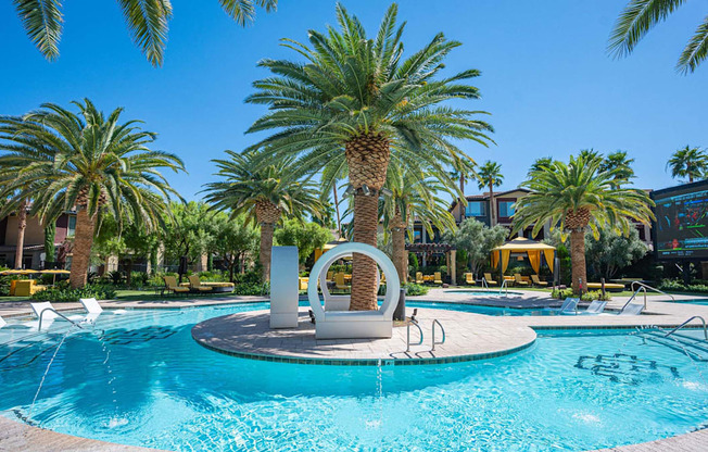 A pool surrounded by palm trees and a white sculpture in the middle.