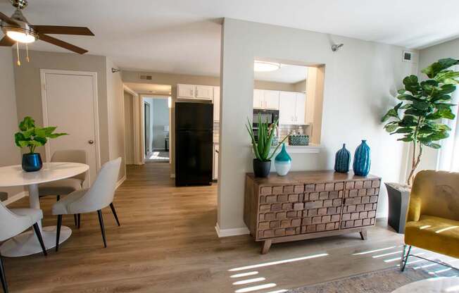 A living room with a white dining table and chairs, a brown brick side table, and a yellow chair.
