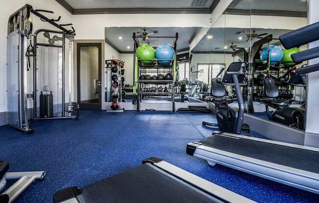 a gym with cardio machines and weights on the floor