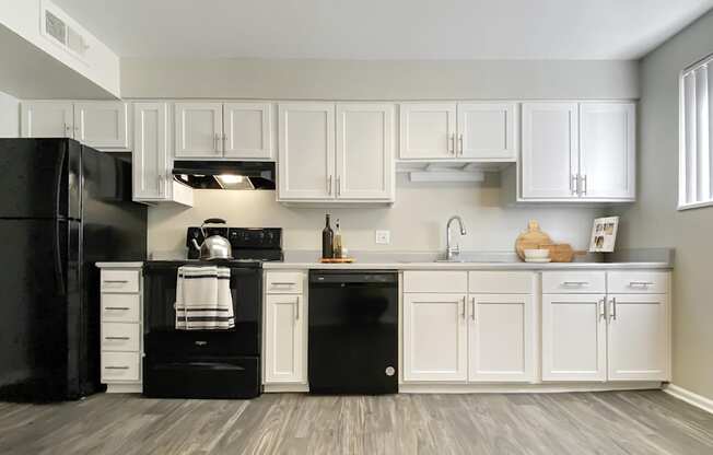 A black refrigerator and oven in a kitchen with white cabinets.