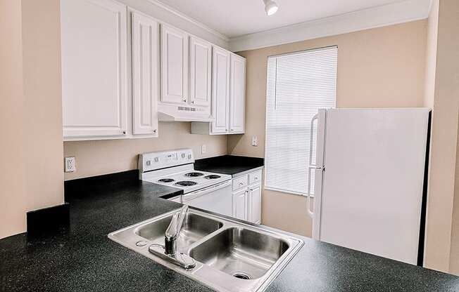 a kitchen with white cabinets and black counter tops and a sink