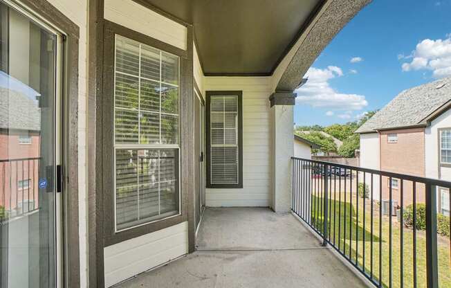 A balcony with a black railing and a view of a blue sky with clouds.