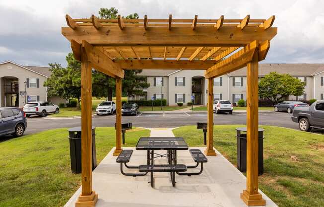 a picnic table under a wooden pavilion on a sidewalk