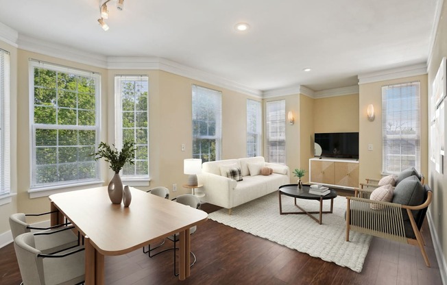 A well-lit living room with a wooden table and chairs.