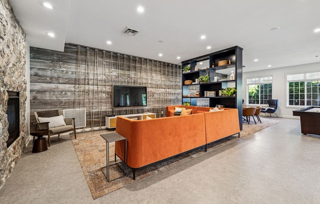 A modern living room with a stone wall and a large orange sofa.
