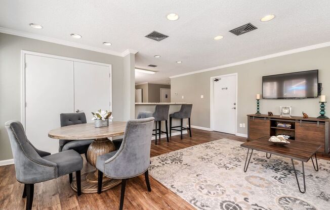 A modern dining room with a round table and grey chairs.