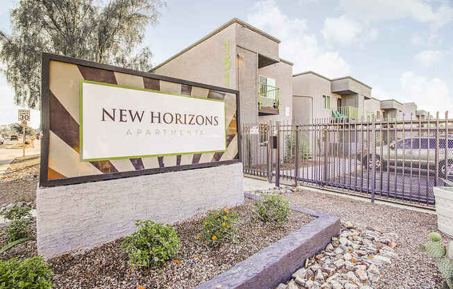 A sign for New Horizons Apartments is displayed in front of a building.