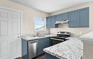 an updated kitchen with granite counter tops and blue cabinets at Diamond Ridge Townhomes, Oklahoma City, 73114