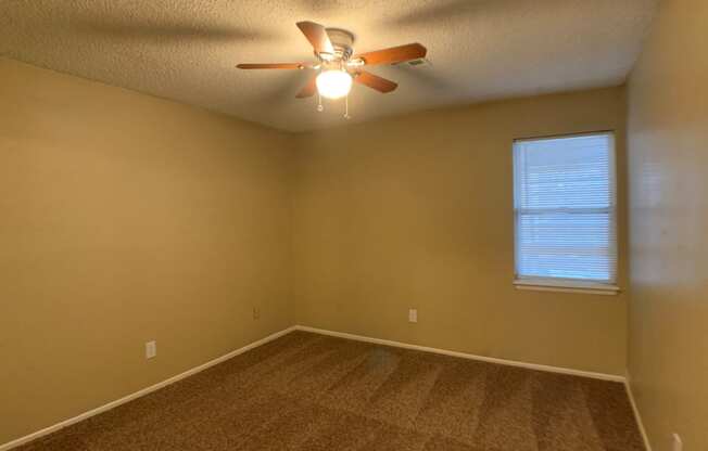 large carpeted bedroom with ceiling fan and window