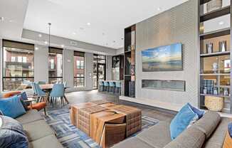 A modern living room with a grey sofa, a wooden coffee table, and a large painting on the wall.