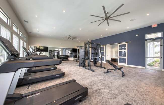 a gym with treadmills and other exercise equipment in a large room with windows