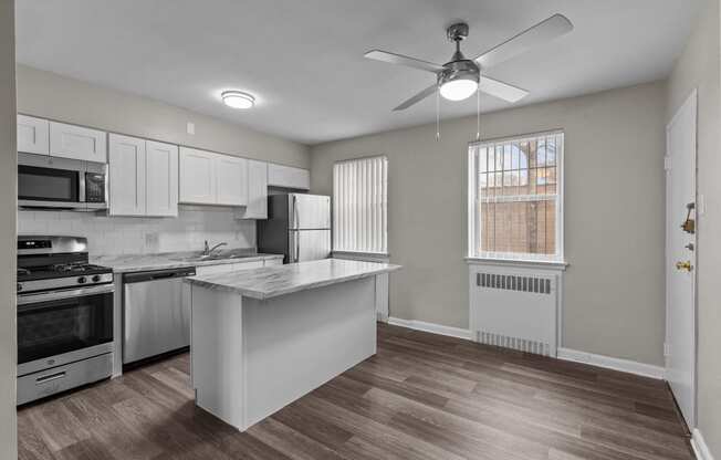 an empty kitchen with an island and a ceiling fan