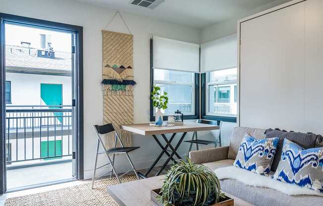 A living room with a couch, a table, and a potted plant.