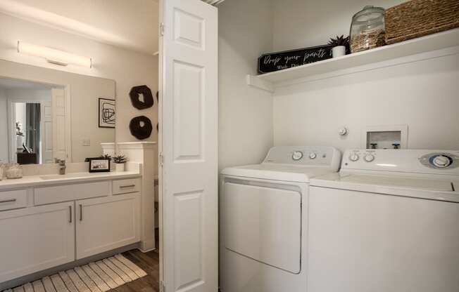 a white washer and dryer in a laundry room with a sink and mirror